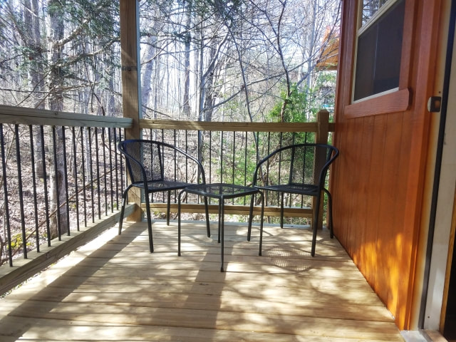 This photo shows the back porch of our Super Cozy Cabins. Pictured are a pair of patio chairs and a small table between them. 