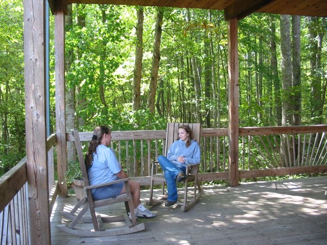Women chatting in rocking chairs on back porch