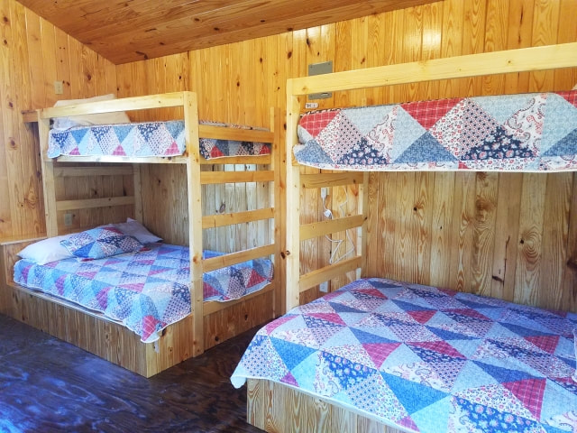 Pictured in this photo is the left side of our Super Cozy Cabins. Shown in the photo are two twin over full bunk beds. These cabins also have a twin over twin bunk on the other side of the cabin (not pictured, for a total of 2 full size beds and 4 twin size beds.