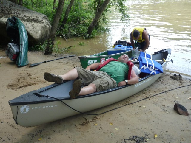 Guy sleeping in canoe on shore