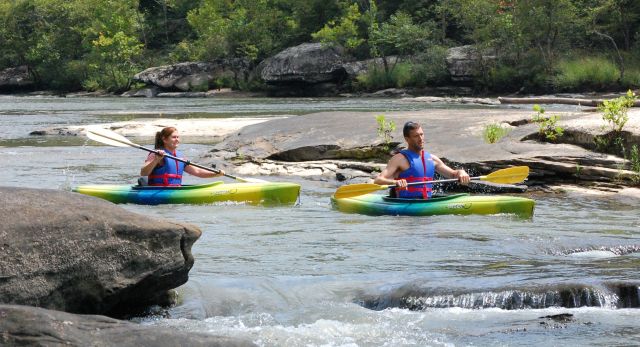 A couple enjoying a day of kayaking through some rocky rapids. 