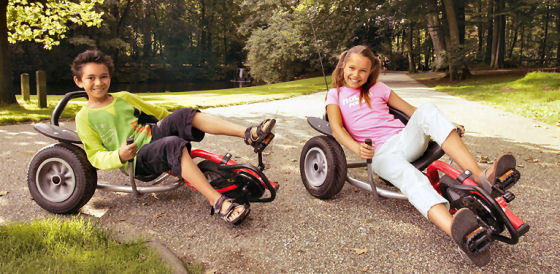 Two kids on three wheeled balance bikes