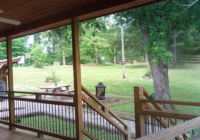 This photo is looking out across the yard from the porch of Star Falls Resort Cabin. You can see the picnic area, equipped with a grill, and a firepit outside. 