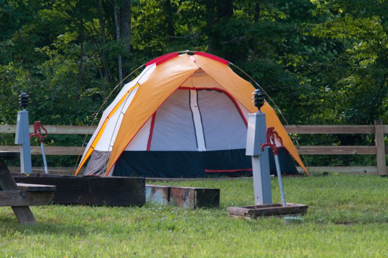 A tent set up on our water and electric tent-site on a summer day. Our fence line can be seen in the background. 